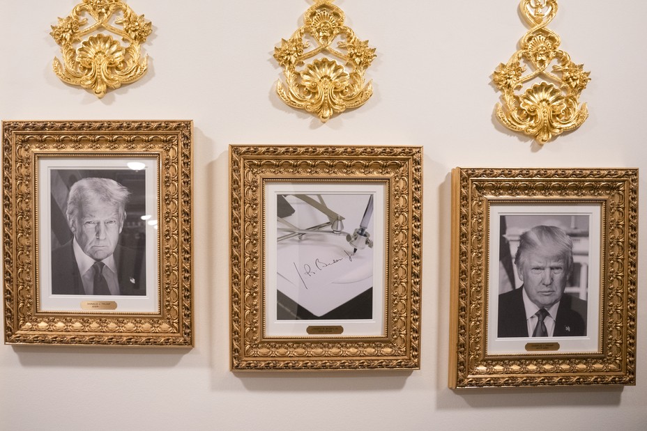 Two black and white photos of Donald Trump and in the middle is Biden's signature, all in gold frames