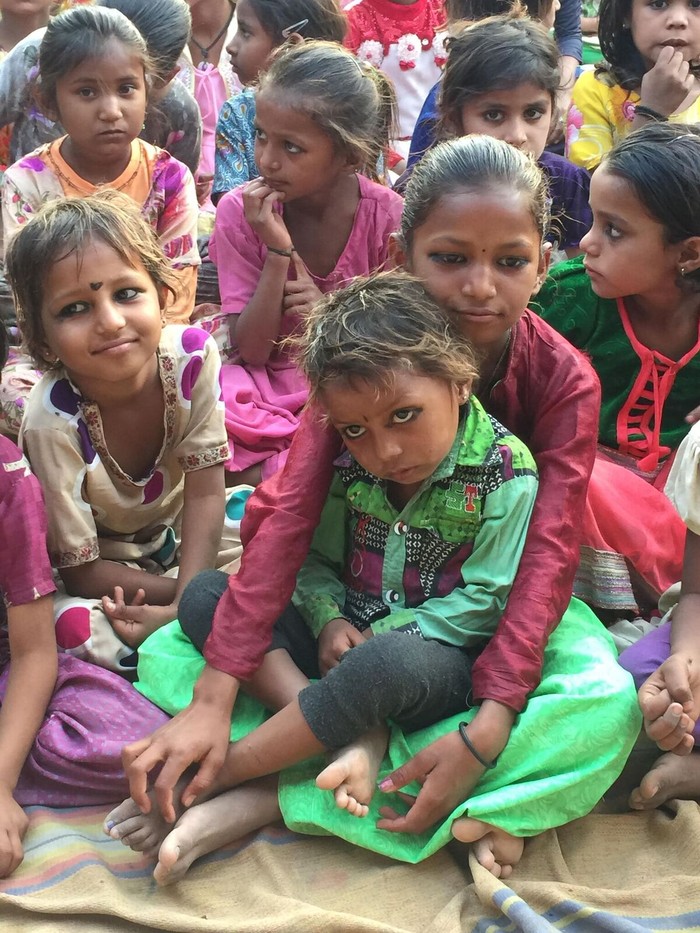 A group of girls sit on the floor. 