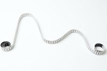 a white measuring tape curled into a graph-like curve with two peaks against a white background