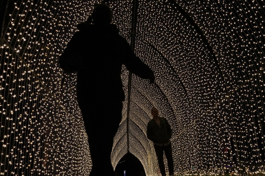 People walk through a tunnel of holiday lights.