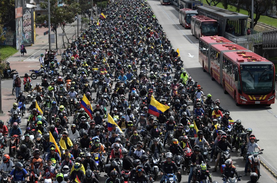 Thousands of motorcyclists take part in a protest, driving down a street.
