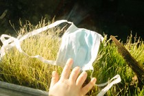 Photo of a child's hand reaching for a surgical mask