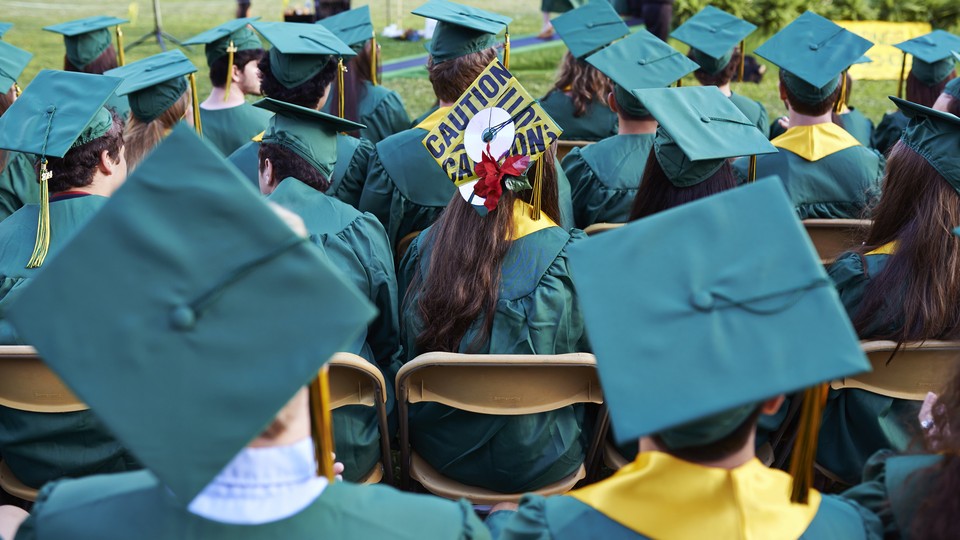 A photo showing students wearing graduating caps, one of which is covered in caution tape.