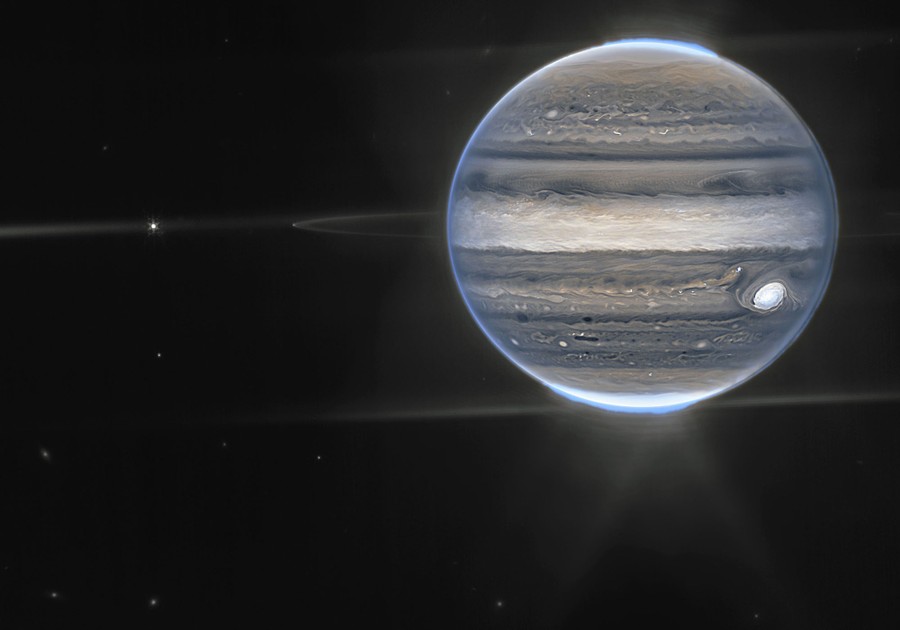 An image of the planet Jupiter, showing its many stripes and glowing auroras at both poles