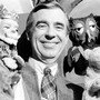 A photo of Fred Rogers holding a few puppets. 