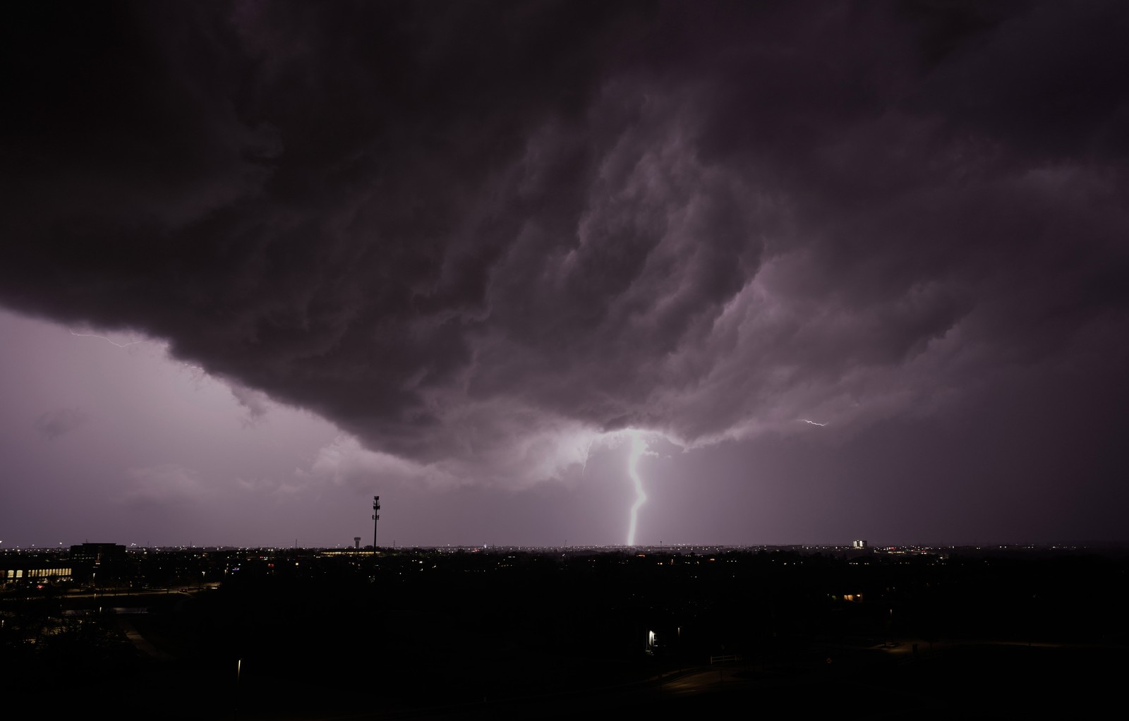 Lightning flashes beneath a dark storm cloud.