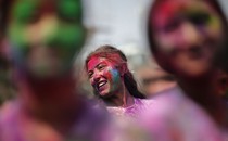 Women smeared with bright colors sing and dance in a street.