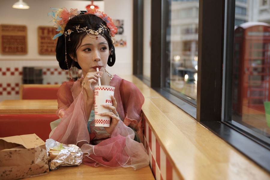 A young woman in traditional dress eats her lunch in a Five Guys restaurant.