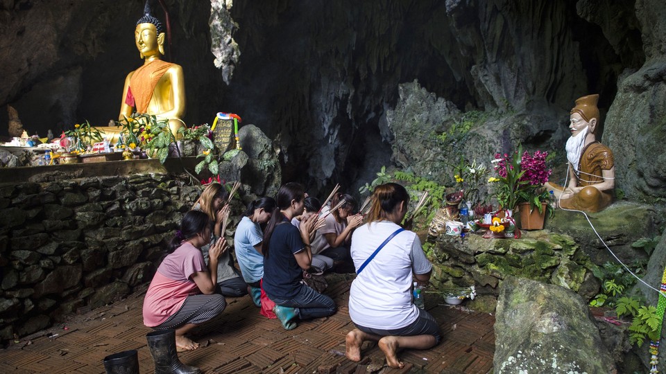 Family members pray before a shrine in Tham Luang cave area as operations were underway for the 12 boys and their coach.
