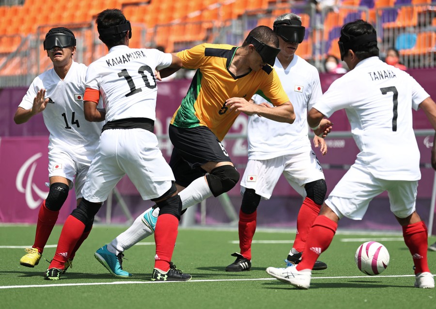Players wearing eye covers face off during a football match.