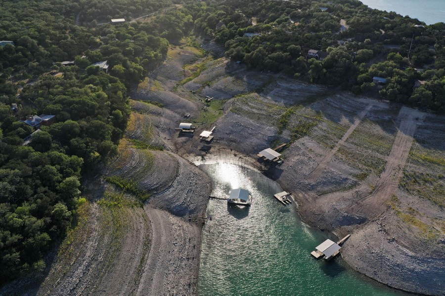 An aerial view of floating docks, some stranded, on the shore of a reservoir that is drying up
