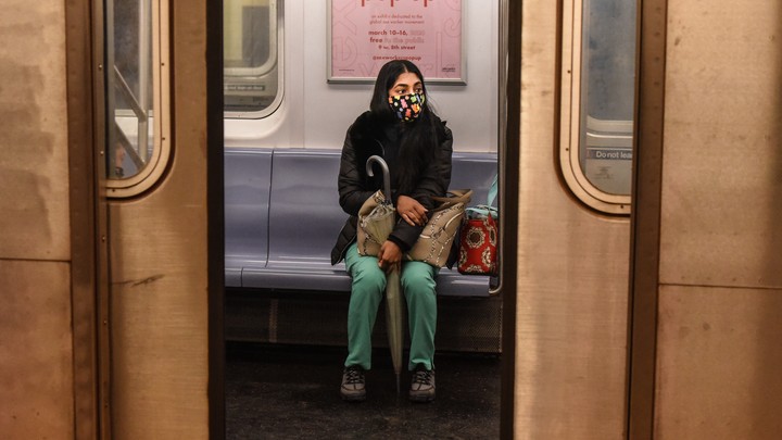 A woman sitting in a subway car with a face ams