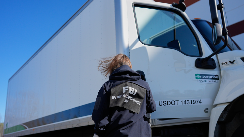 An agent with the FBI Evidence Response Team stands in Fulton County with her back to the camera, facing a large truck