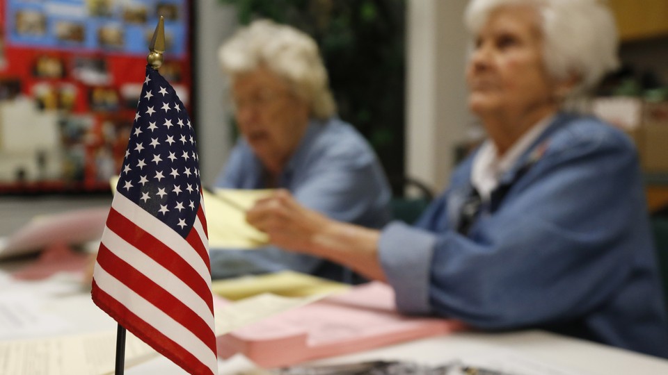 An American flag sits on the table where two Oklahoma poll workers are helping voters.