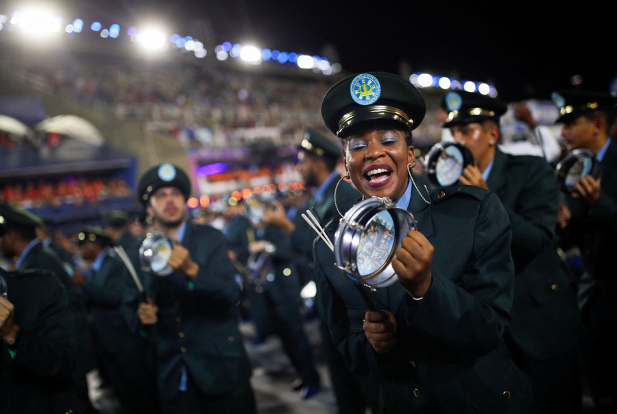People play small drums as they march in a parade.