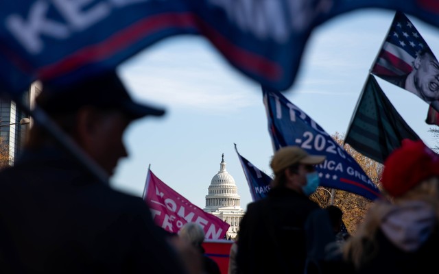The U.S. Capitol is seen through a group of pro-Trump protesters waving flags on the streets of Washington, D.C.