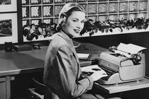 The actress Grace Kelly sitting at a table with a Remington typewriter