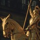 A golden statue of Joan of Arc looking defiant on her horse.