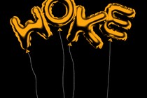 Gold letter-shaped balloons spelling out the word “woke”