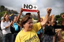 Opposition supporters holding a placard that reads, "No more dictatorship" shout slogans.