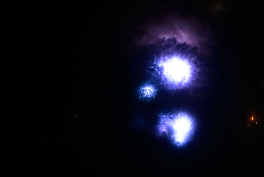 Several lightning strikes, seen in clouds, viewed from above
