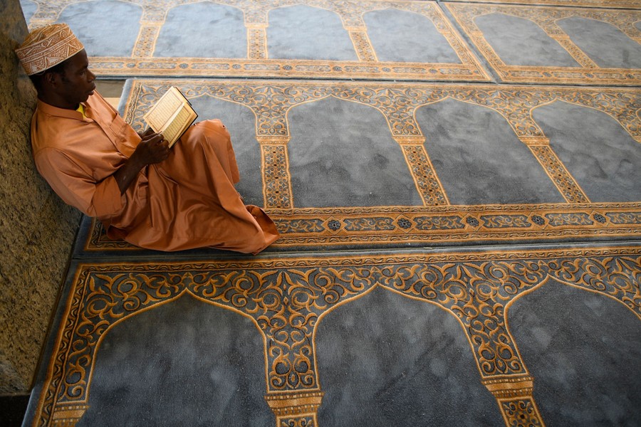 Ένα άτομο κάθεται στο πάτωμα και μελετά το Κοράνι.