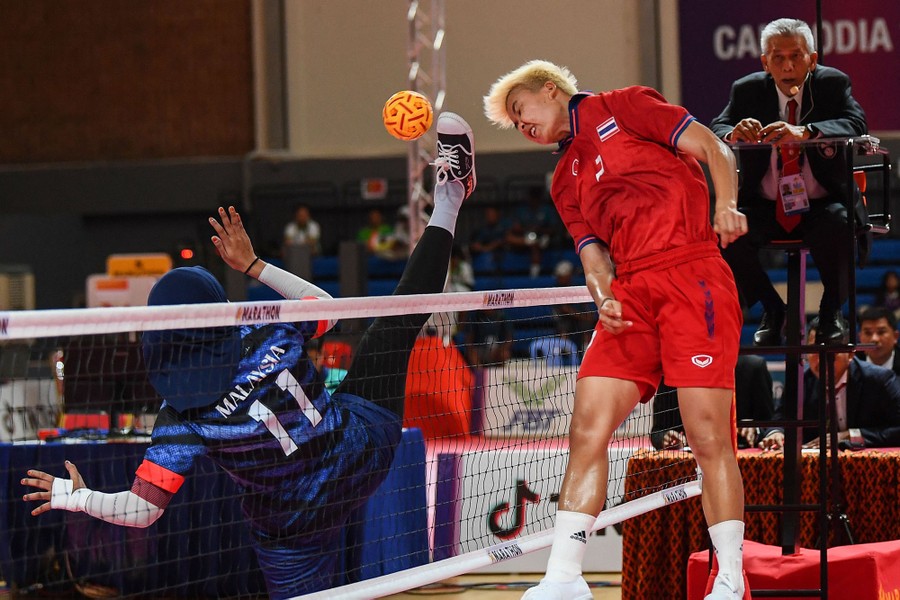 An athlete leaps beside a net to block a kicked ball.