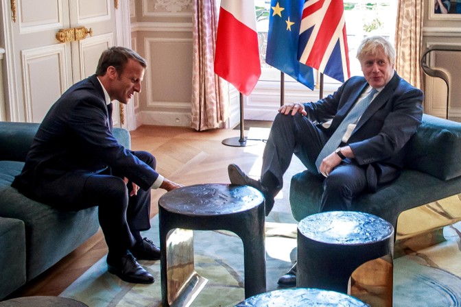 Boris Johnson puts his foot up on a table as he sits opposite Emmanuel Macron.