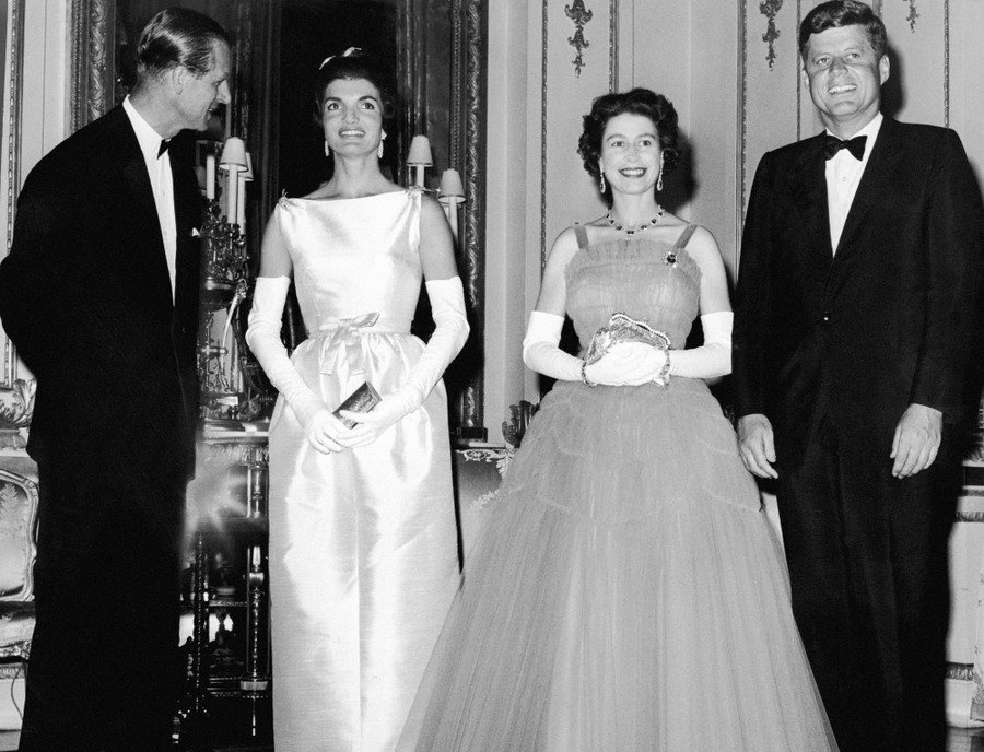The Duke of Edinburgh, Jackie Kennedy, Queen Elizabeth, and President Kennedy stand next to one another in a line, wearing evening clothes