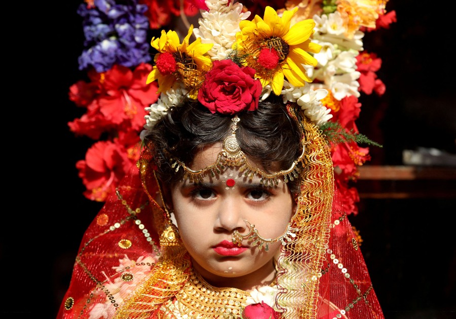 A young girl wears an ornate costume and a flower headdress.