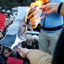 Protesters burn a picture of Vladimir Putin.