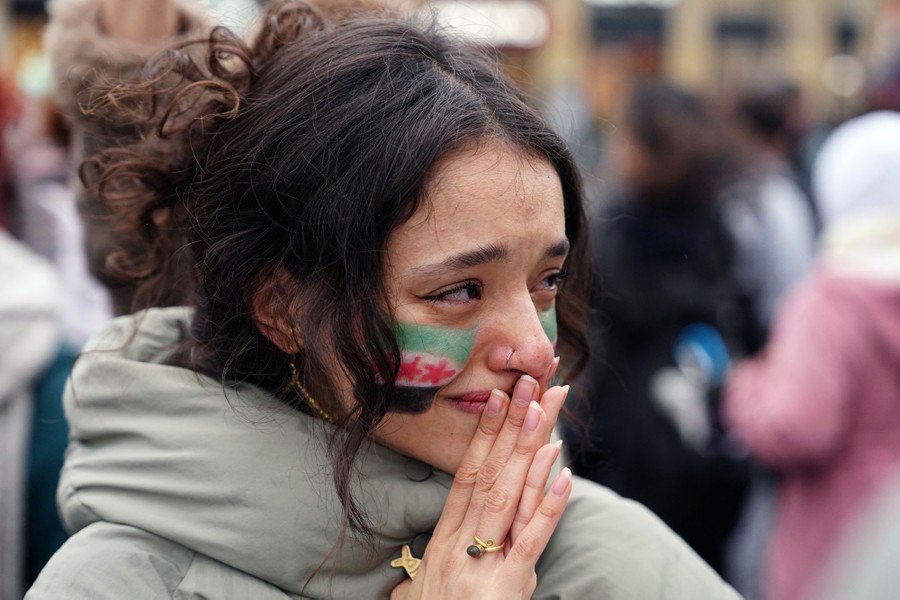 An emotional person looks on during a celebration in a city square.