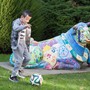 A little boy playing soccer next to a colorful statue of a cow