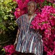 The author Ngũgĩ wa Thiong’o standing in front of pink flowers in an African-made shirt