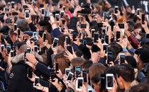 A crowd of people taking photos with smartphones