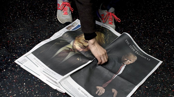 A newspaper bearing Donald Trump's image is picked up off the floor.