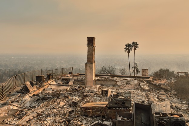 Color photo of debris from a house completely destroyed by wildfire except its fireplace chimney.