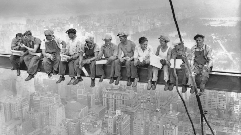 A group of steel workers eats lunch on a beam hundreds of feet above New York City.