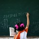 A girl wearing pigtails does math problems on a chalkboard 