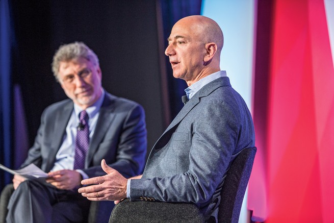 photo of Marty Baron and Jeff Bezos seated onstage at an event, with Bezos speaking
