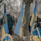 Ukrainian military men and civilians holding Ukrainian flags in a cemetery