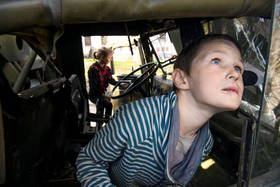 Two children play in the cab of a destroyed Russian military truck.