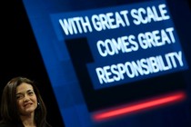 Sheryl Sandberg grimaces in front of a large slide that says “WITH GREAT SCALE COMES GREAT RESPONSIBILITY.”