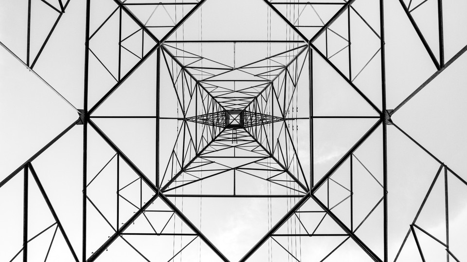 A black-and-white image of a transmission tower photographed from underneath