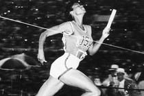 a woman running across the finish line in a track relay race