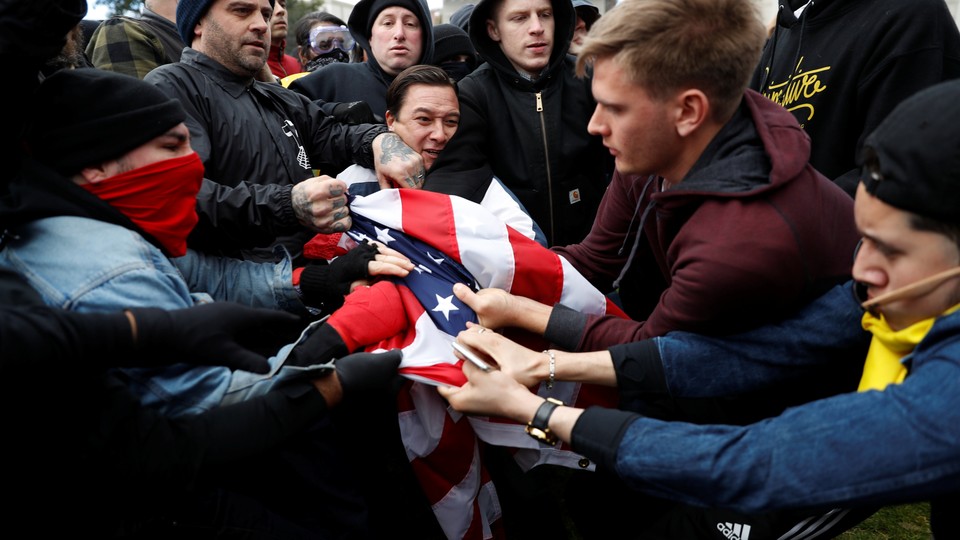 People in sweatshirts and jackets grab at an American flag.