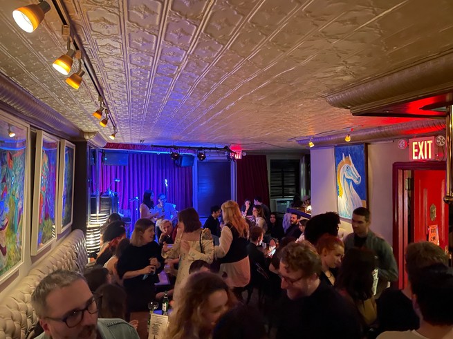 A crowded bar with a white tin ceiling.