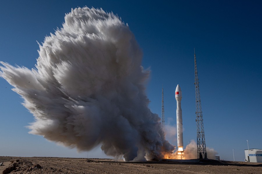 A launching rocket blasts a large plume of water and smoke upward.