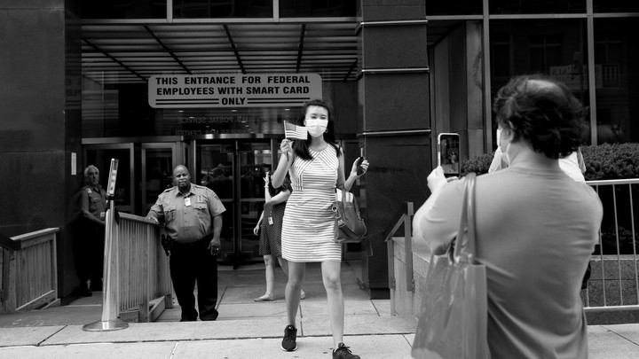 Amy’s father takes her photo as she walks out of the USCIS building an American citizen.