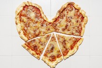 A heart-shaped pizza with slices cut out